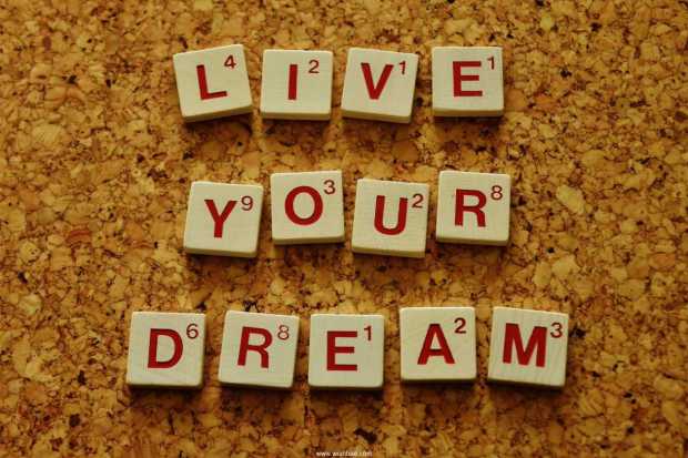 Live your dream spelled out in scrabble tiles on a cork board background