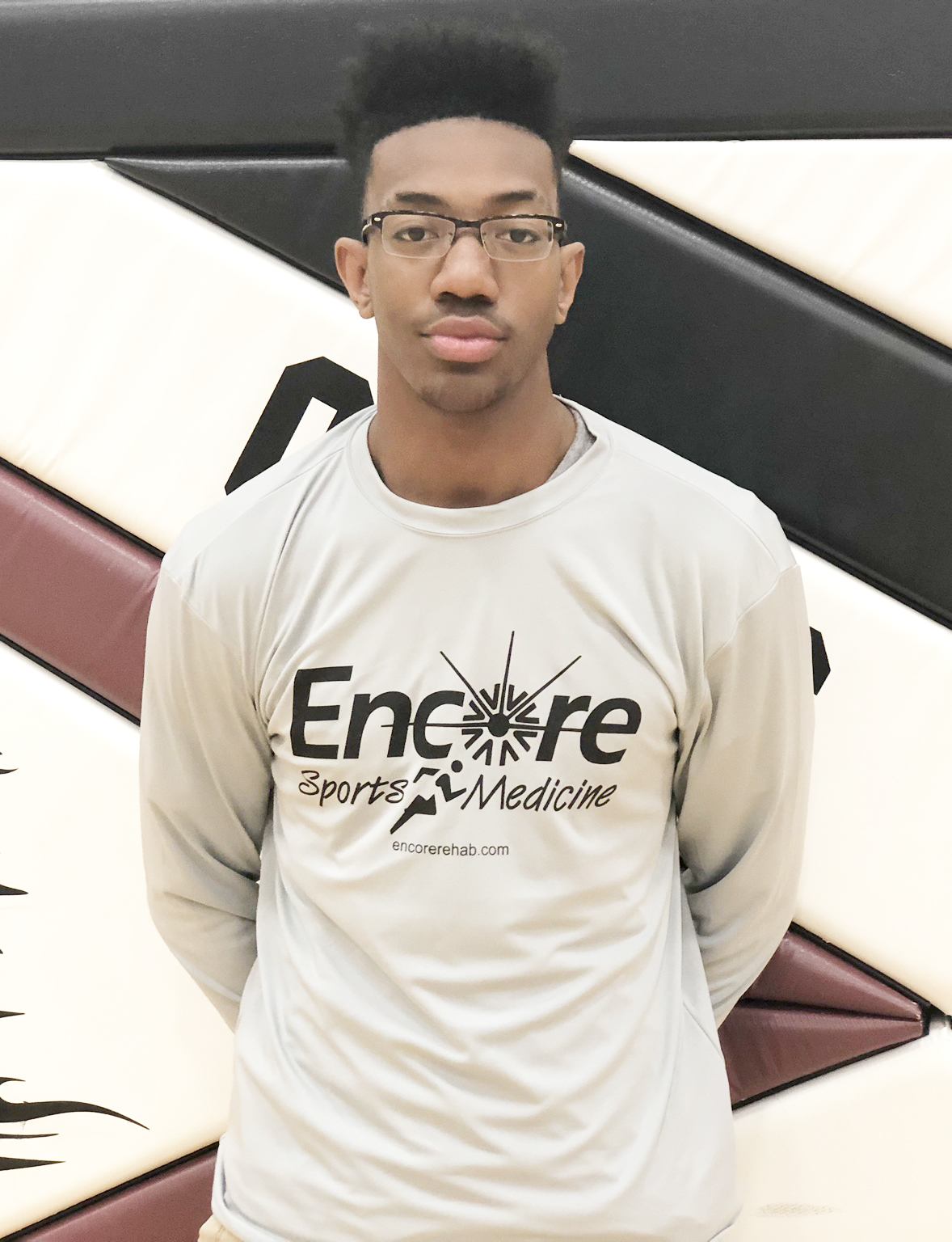 Young male athlete standing in gym with shirt that reads Encore Sports Medicine, encorerehab.com