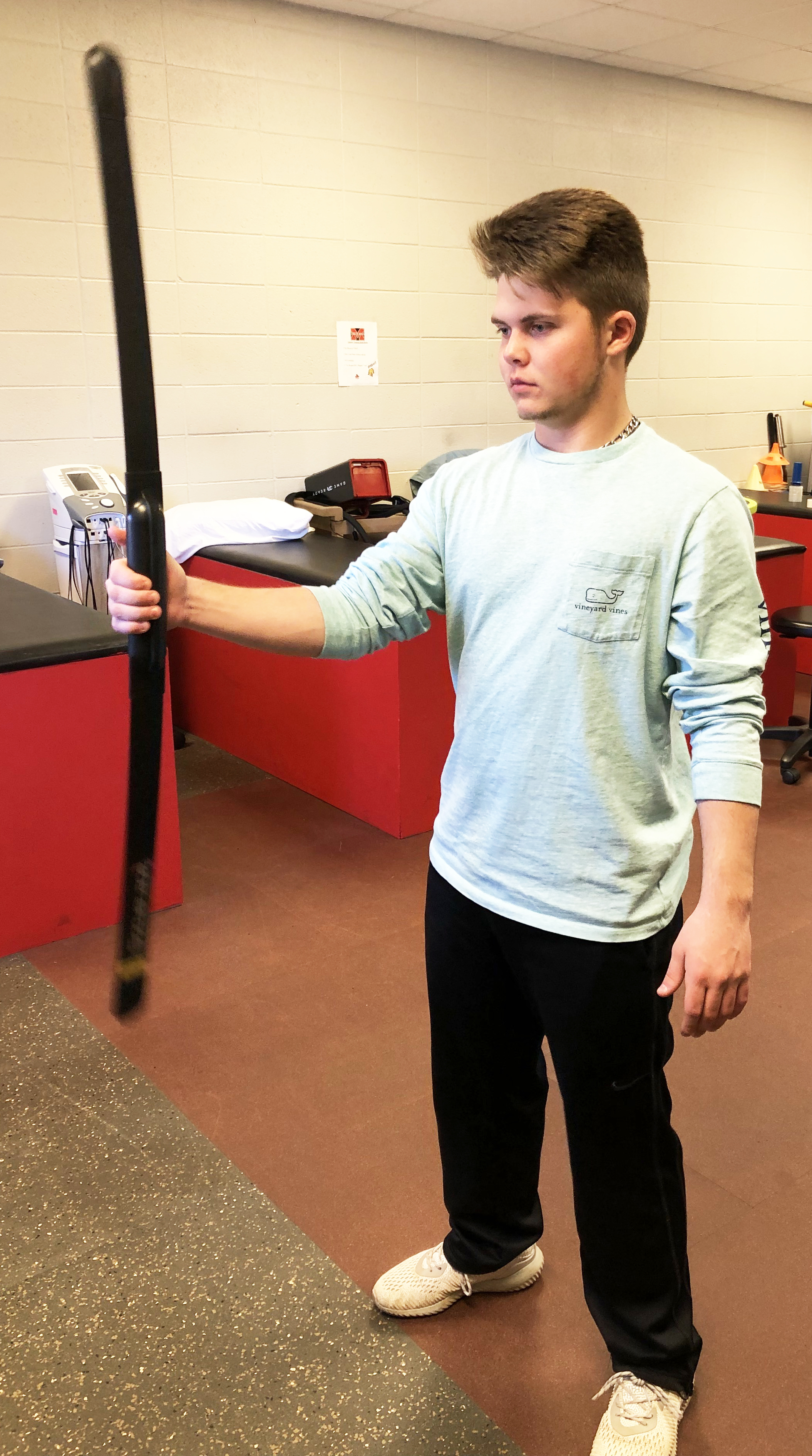 Young man holding a resistance blade exercise bar out from body