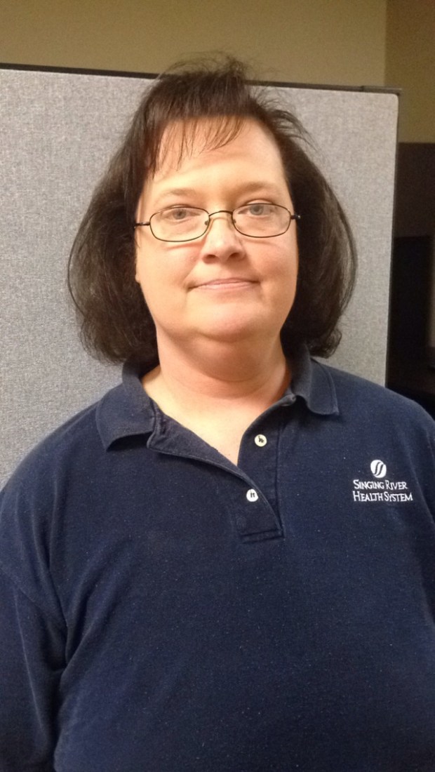 Female Physical Therapist Assistant with glasses and navy polo shirt smiling