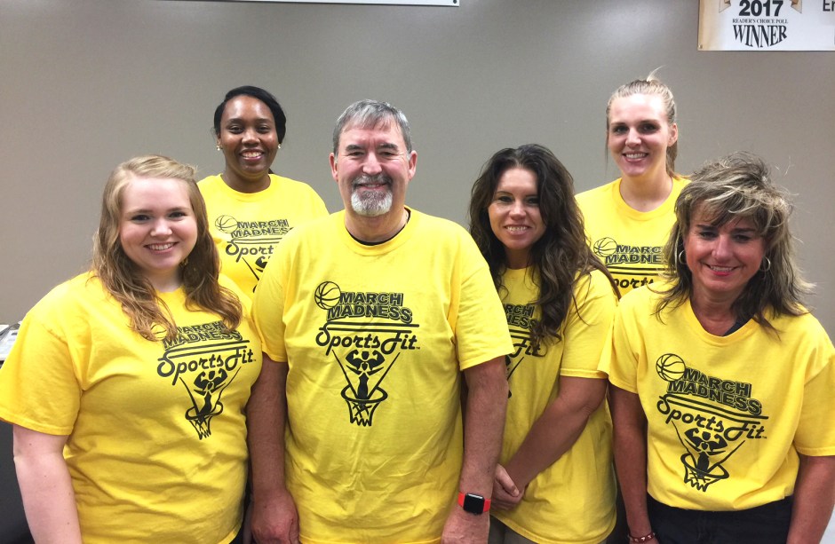 Six individuals posing for photo while wearing SportsFit March Madness t-shirts.