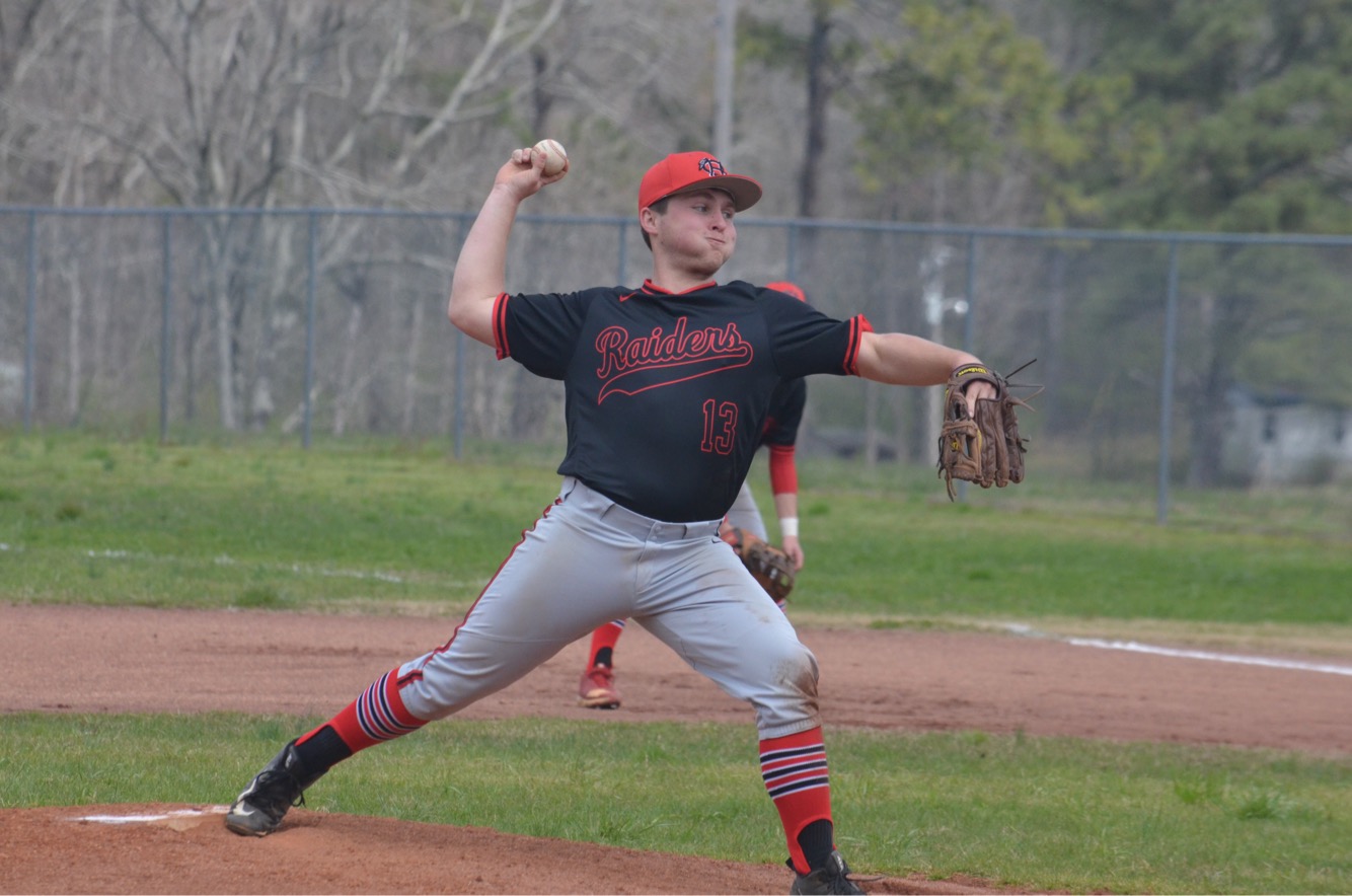 Teenage boy in baseball uniform pitching a baseball