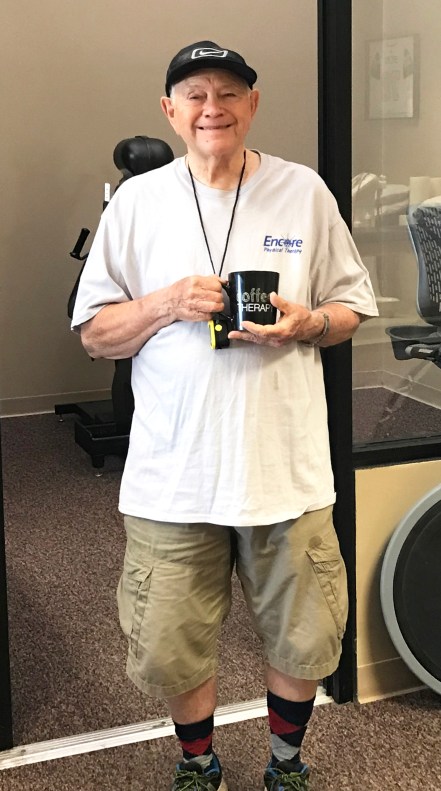 Man smiling, standing with coffee cup in hand. Man is Gordon Coats, Patient of the Month for Encore Rehabilitation-Tuscaloosa.
