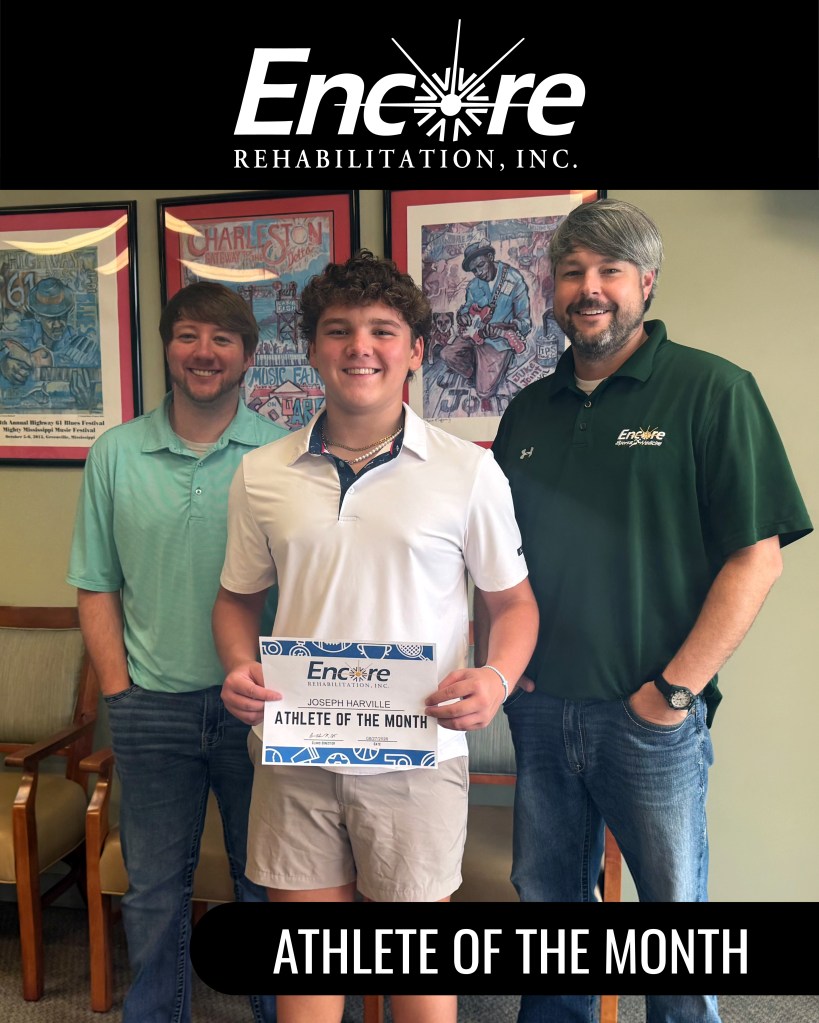 male youth smiling and standing with two adult males, his rehab team at Encore Rehabilitation-Grenada, MS