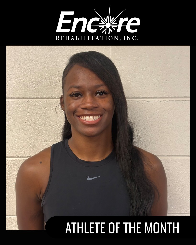 A smiling athlete wearing a black sleeveless top, featuring the Nike logo, stands against a light-colored wall. The image highlights her as the 'Athlete of the Month' for Encore Rehabilitation, Inc.